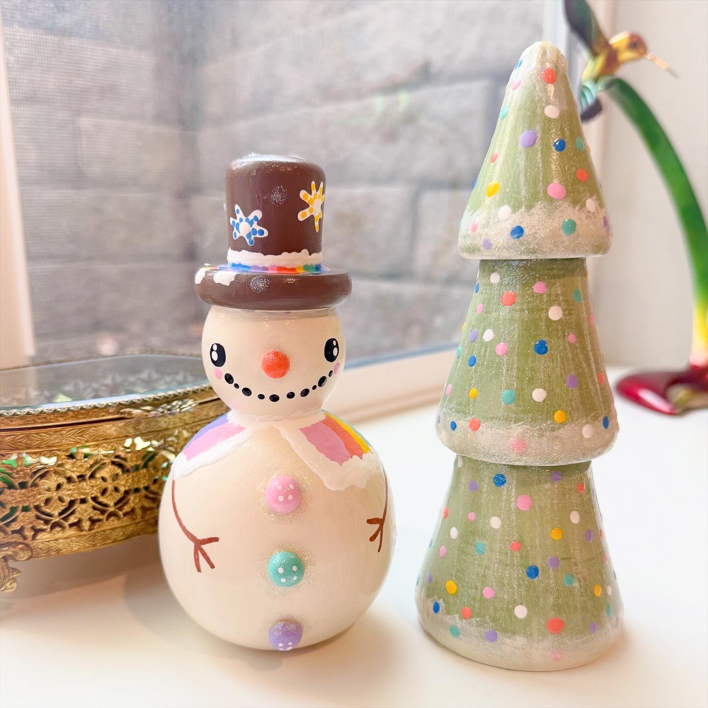 Decorative snowman figurine and polka dot tree on a light surface with a blurred background