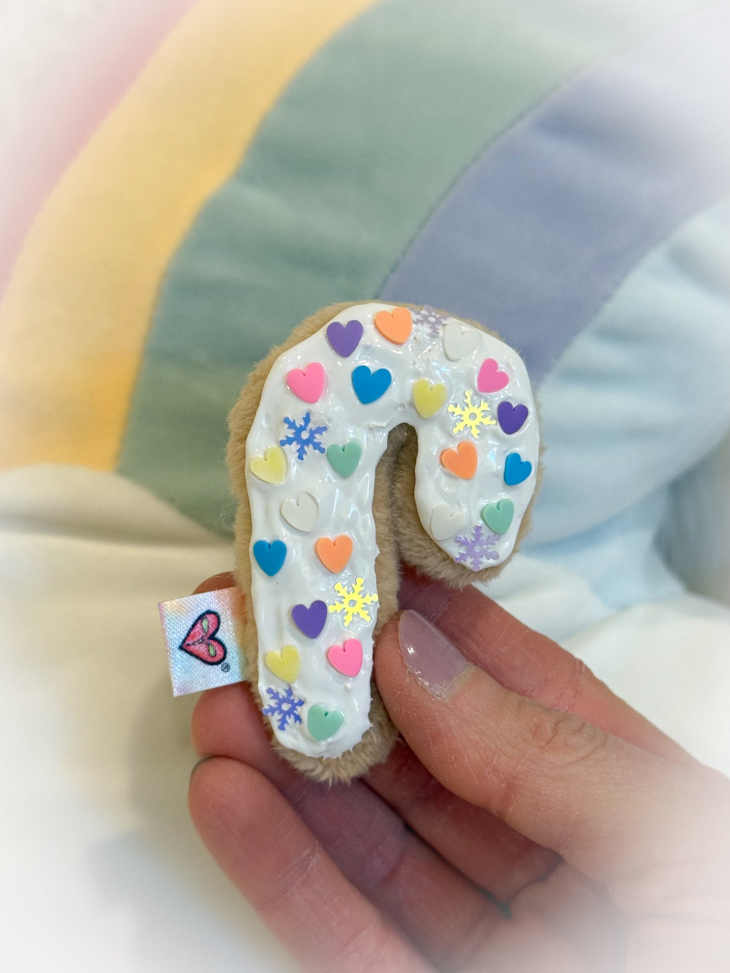 Decorative cookie with colorful icing held by a hand against a soft, blurred background